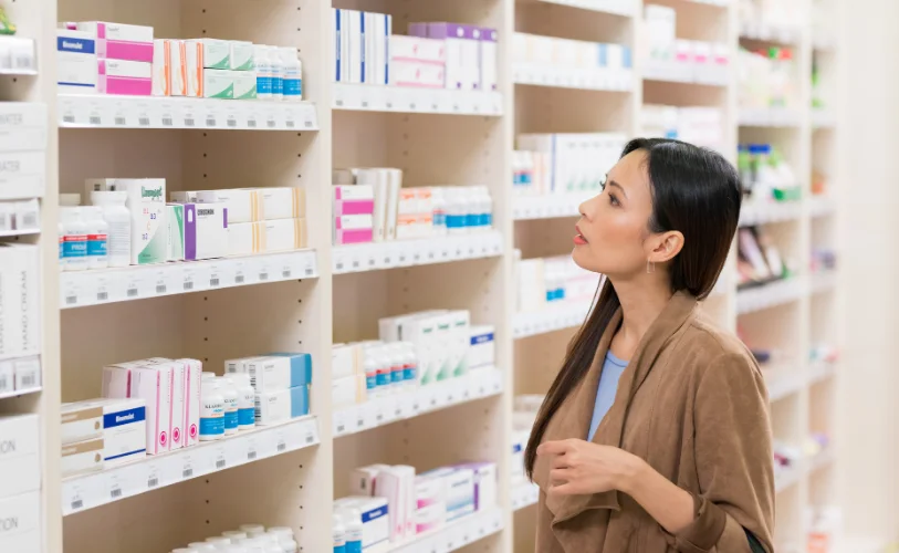 A customer browsing health products on pharmacy shelves